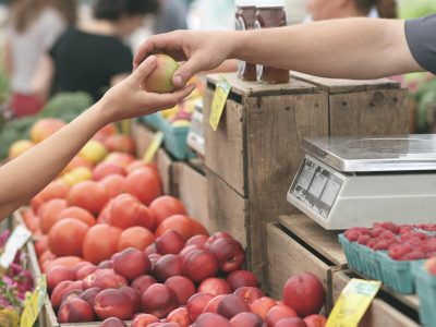 Weniger Verpackungsmüll, mehr Nachhaltigkeit. Hand reicht ein Stück Obst an andere Hand. Dies symbolisiert Nachhaltigkeit im Alltag.